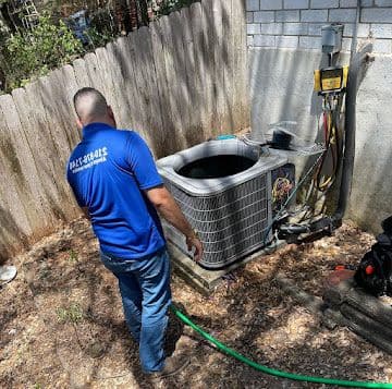 Technician performing an AC maintenance tune-up in a backyard